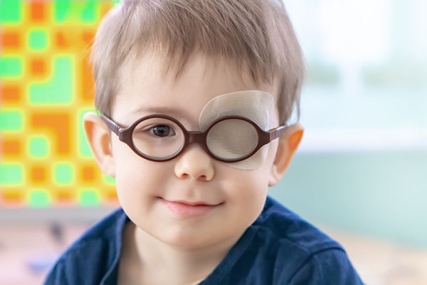 boy wearing glasses with eye patch